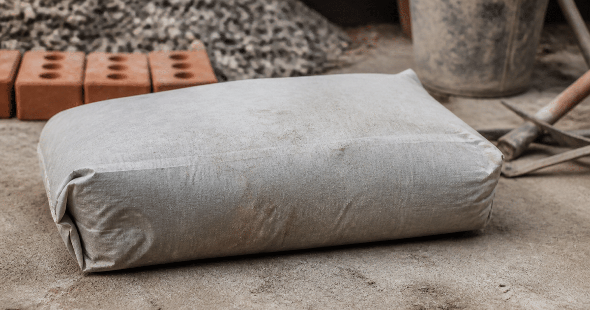 Sac de ciment gris posé horizontalement avec materiaux de construction