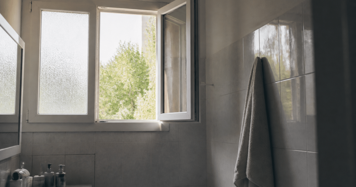 Fenetre ouverte laissant entrer air frais dans salle bain carrelée