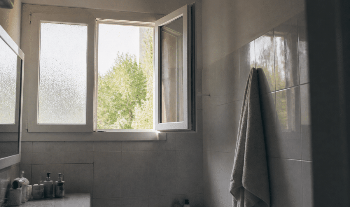 Fenetre ouverte laissant entrer air frais dans salle bain carrelée
