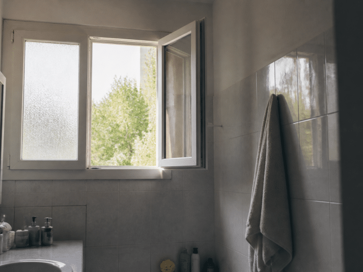 Fenetre ouverte laissant entrer air frais dans salle bain carrelée