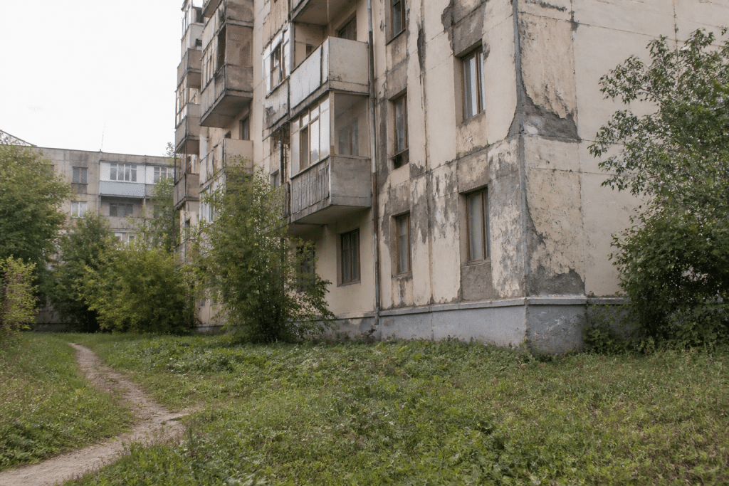 Immeuble delabré avec façades endommagées et espaces verts négligés