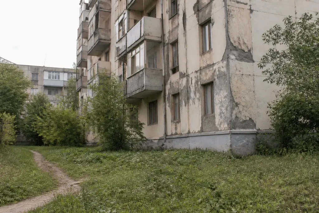 Immeuble delabré avec façades endommagées et espaces verts négligés