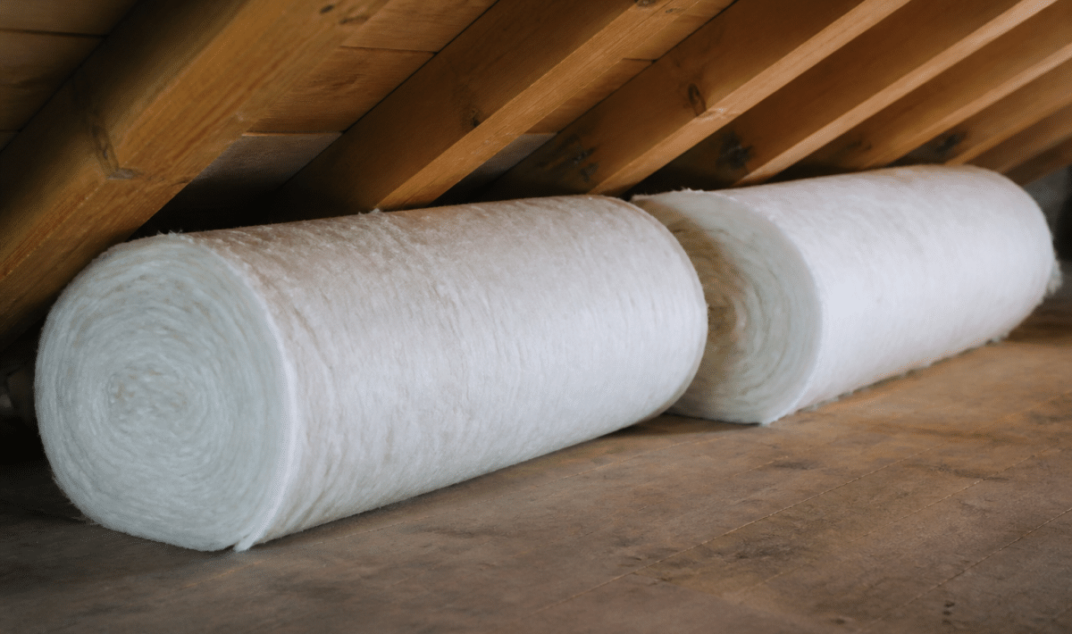 Rouleaux isolants blancs poses horizontalement sous charpente bois