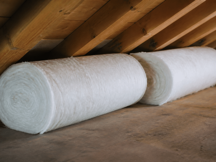 Rouleaux isolants blancs poses horizontalement sous charpente bois