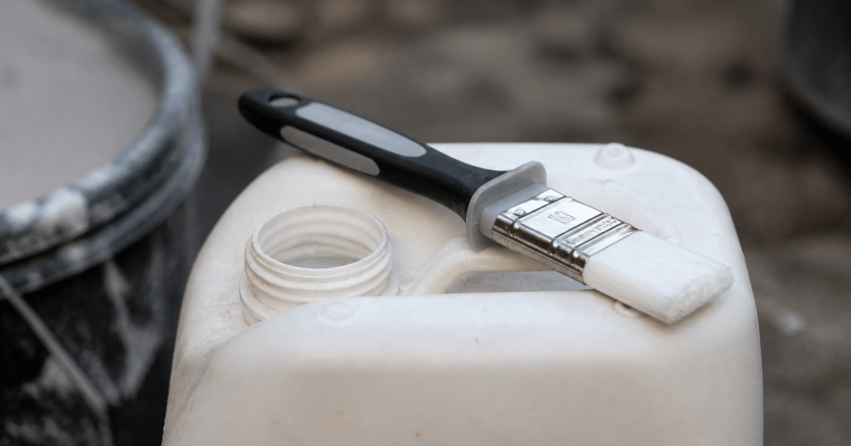Pinceau applicateur grip posé sur bidon apprêt blanc