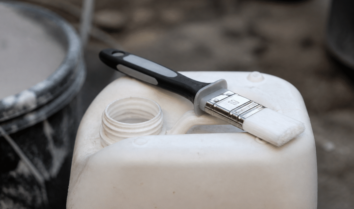 Pinceau applicateur grip posé sur bidon apprêt blanc