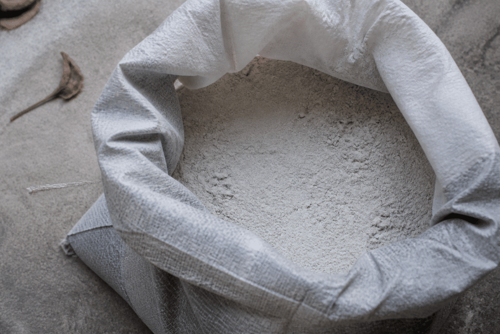 Sac gris de ciment ouvert montrant poudre fine blanche
