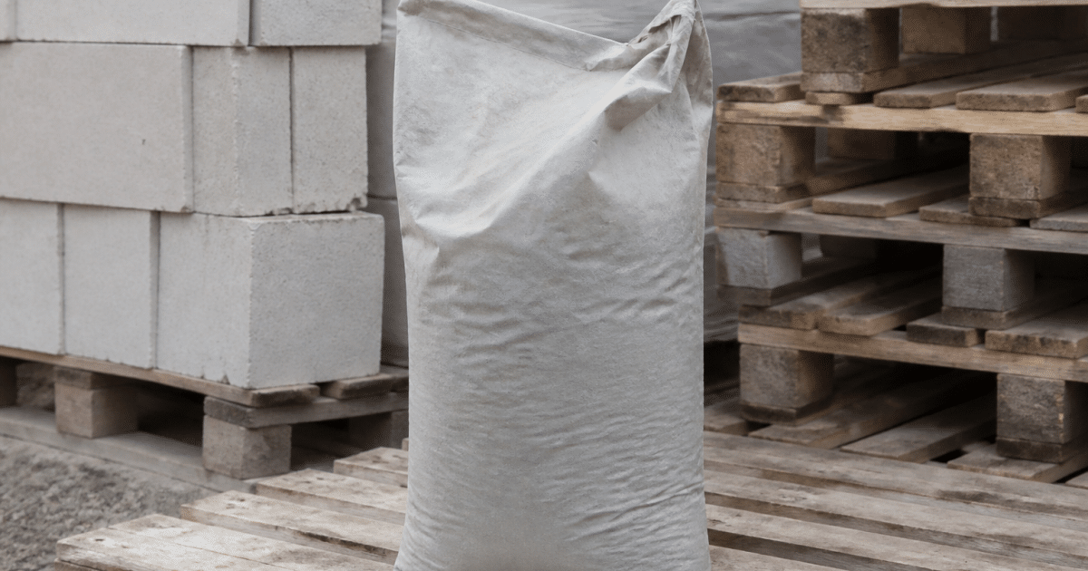 Sac gris ciment trente-cinq kilogrammes posé verticalement sur palette