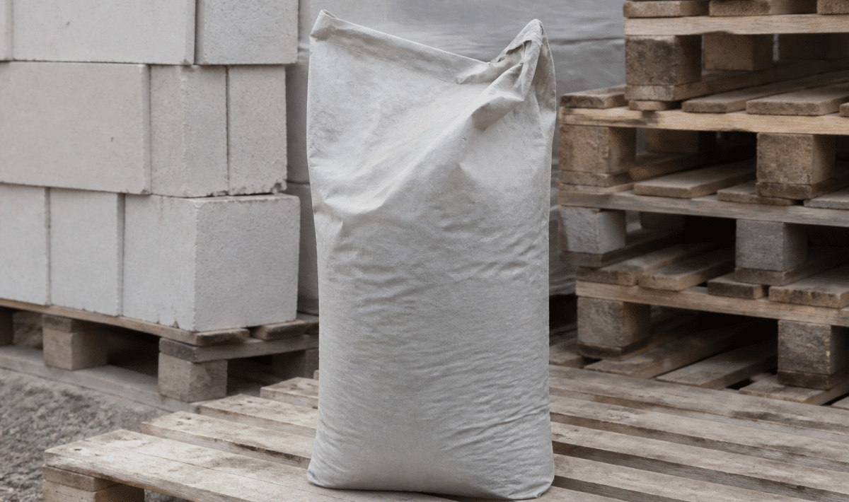 Sac gris ciment trente-cinq kilogrammes posé verticalement sur palette