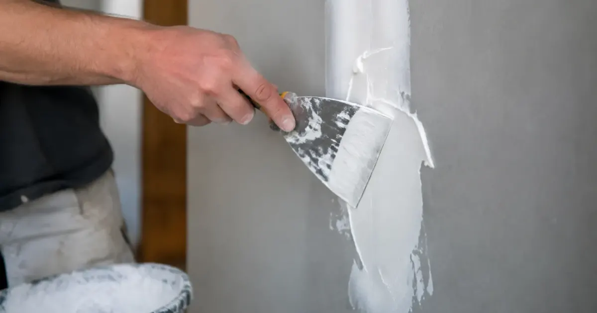 Main etalant pate adhesive blanche sur panneau gris vertical