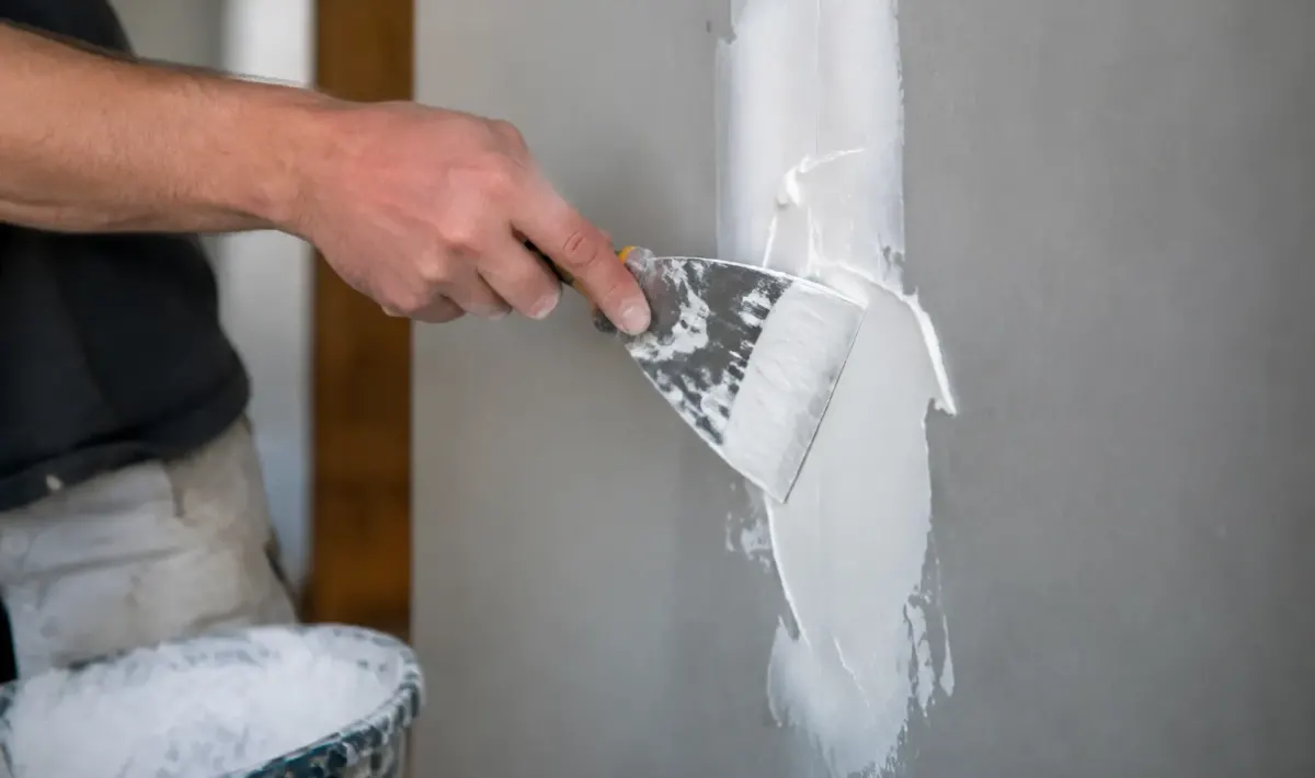 Main etalant pate adhesive blanche sur panneau gris vertical