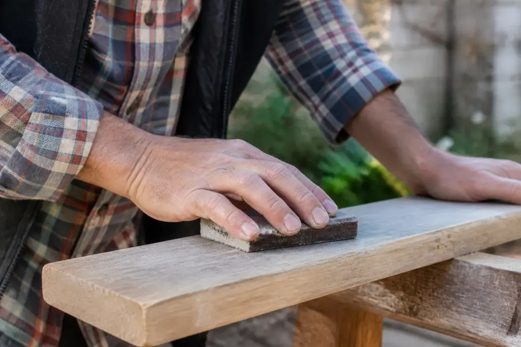 Main tenant cale abrasive sur planche de bois