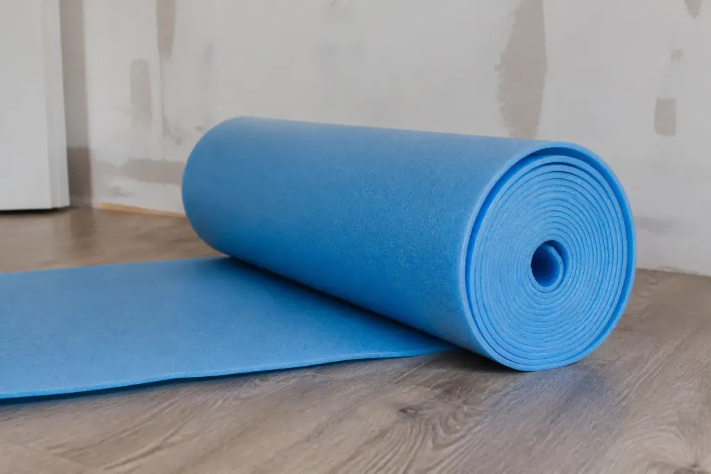 Rouleau bleu de mousse isolante sur lattes de parquet