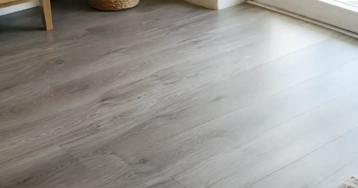 Lames vinyle grises colles sur du carrelage blanc